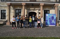 grupa młodzieży bioraca udział w zajęciach, zdjęcie pzred pałacem